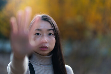 Asian young woman showing stop gesture with hands