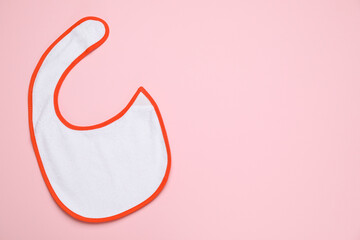 New baby bib on pink background, top view. Space for text