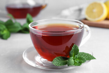 Cup of hot aromatic tea with mint on light grey marble table, closeup