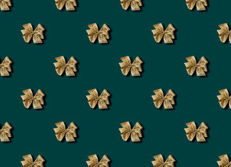 Golden bow for decorating gifts on a green background. Beautifully tied bow. Photo of a gift package with a seamless pattern.