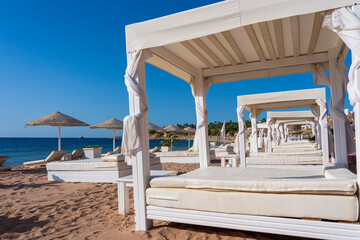 White sun canopy with mattress on luxury sand beach in tropical resort in Red Sea coast in Egypt,...