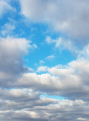 Big white fluffy clouds in the blue sky in sunny weather, vertical format