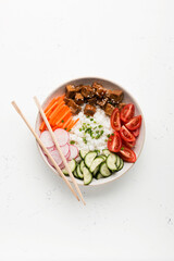 Poke bowl, lunch bowl with fresh vegetables and rice. Asian chopsticks