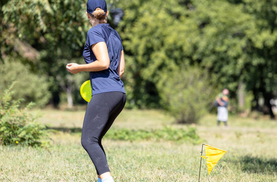 Young woman playing flying disc golf sport game in the park