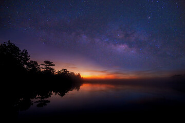 Fototapeta na wymiar Beautiful milky way on the reservoir and the pine forest