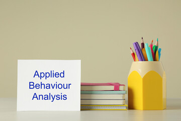 Set of stationery and card with text Applied Behavior Analysis on wooden table against beige...