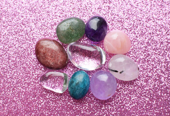 Gemstone minerals on a pink background. Round tumbling minerals of amethyst, rose quartz, apatite,...