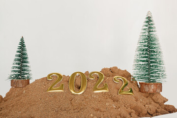 Concept  happy new year 2022  on floor sand ,and christmas tree with white background