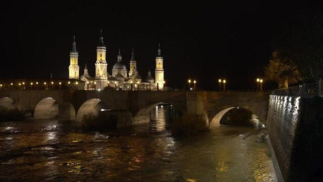 Night video from the stone bridge next to the Basilica of Nuestra Señora del Pilar over the Ebro river in the city of Zaragoza, Aragon. Spain, 4k video