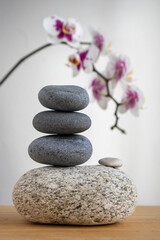 Obraz na płótnie Canvas Stack of gray stones built in tower isolated on white background with white purple orchid flower on long stem