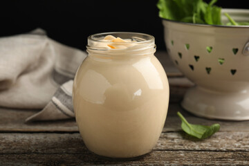 Jar of delicious mayonnaise and fresh spinach on wooden table