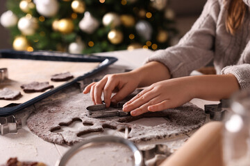 Fototapeta na wymiar Little child making Christmas cookies at white wooden table, closeup