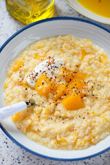 Close-up of millet porridge with pumpkin and soft cheese, vertical shot, selective focus