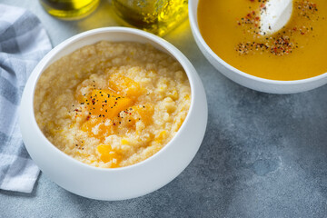 Millet porridge with pumpkin and pumpkin soup served in white bowls, horizontal shot on a light-blue stone surface