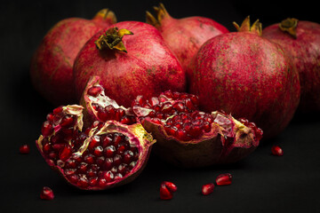 Garnet fruits and pulp on black background. Fresh pomegranate fruits and seeds close up. Healthy...