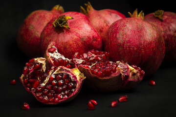 Garnet fruits and pulp on black background. Fresh pomegranate fruits and seeds close up. Healthy vitamin fruits