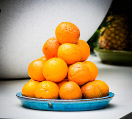 A lot of fresh orange stack up on the blue ceramic tray.