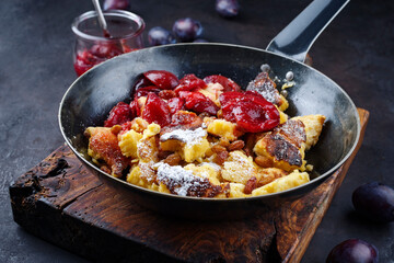 Traditioneller österreichisch Kaiserschmarren mit Zwetschgen und Rosinen serviert als Draufsicht in einer rustikalen Bratpfanne 