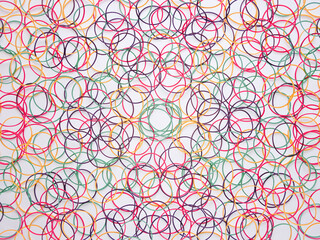 白背景に沢山散らばった色付きの輪ゴム。カラフルな背景素材。