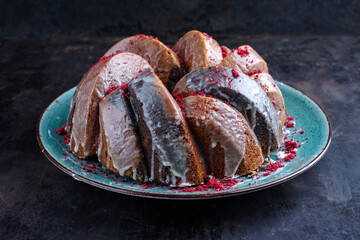 Traditional exotically bundt marble cocoa chocolate cake with icing sugar glaze and freeze dry raspberry topping served as close-up on a Nordic design plate with copy space
