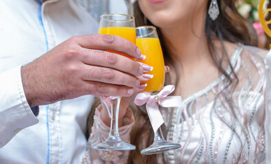 The bride and groom are holding glasses with juice in their hands.