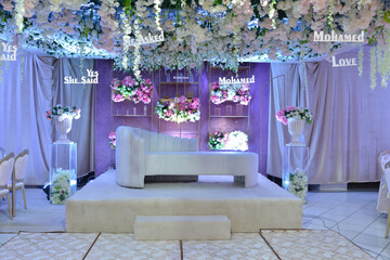 An elegantly staged traditional MOROCCAN style wedding with large sofa for the wedding couple to sit and receive blessings from the guests, surrounded by beautiful floral decor and candle light 