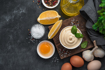 Mayonnaise, and ingredients for cooking: eggs, lemon and butter on a black background.