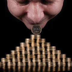 100 Kazakhstani tenge coins stacked in the form of a pyramid and mans face