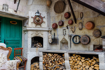 Wall decorated with various objects near a limestone fireplace, stacked firewood