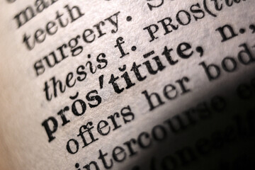 Word "prostitute" printed on dictionary page, macro close-up		