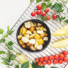 Vegan picnic with young potatoes and seasonal vegetables. Summer healthy, food composition with a bowl with farm, young potatoes and seasonal vegetable on a grill on a white background