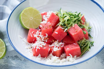 Close-up of salad with watermelon cubes, grated cucumber and bryndza cheese served in a white plate