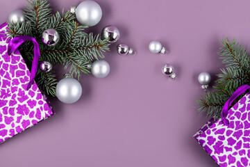 The concept of a Christmas background. Top view of silver balls from a Christmas gift box with fir branches on a fashionable purple background.