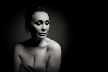 Fototapeta premium Portrait of a sensual fifty year old woman on grey studio background. Monochrome shot.