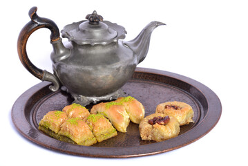 Fresh oriental pastries, so-called baklava, lie on a tray made of hammered copper with an old tin...