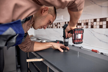 Handyman making kitchen wall cabinets in the apartment.