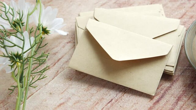 stack of envelope , flower and cup of tea on table 