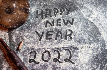 Happy New Year 2022 on Wheat Flour with Wooden Rolling Pin and Board in Kitchen