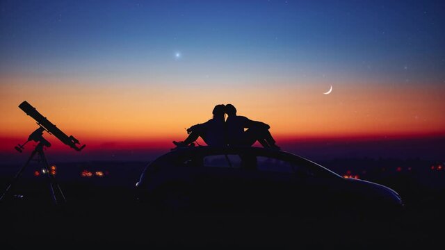 Couple stargazing together with a astronomical telescope.