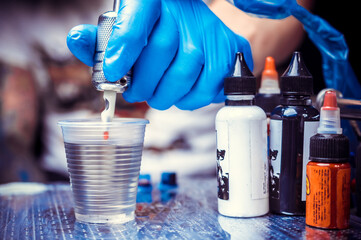 Hand of a tattooer, holding a tattoo gun.