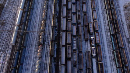 Aerial view of railway wagons with coal and tanks on an industrial railroad during the winter