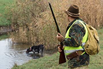 Hunter man in camouflage with a gun during the hunt in search of wild birds or game. Autumn hunting...