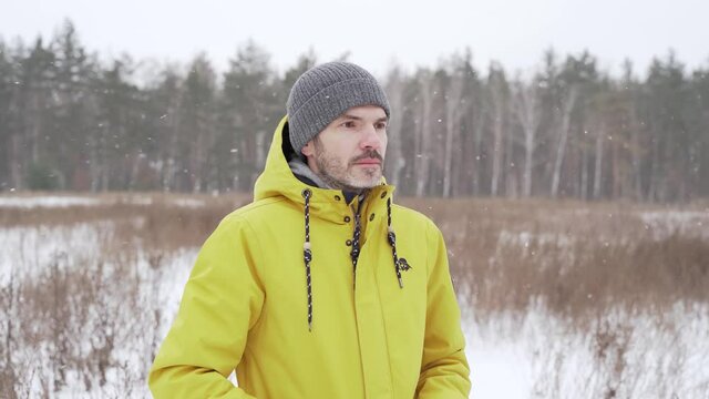 Man in a yellow jacket who stands in a snowfall on a field