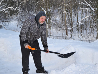 A strong Man shovels snow on the street in winter