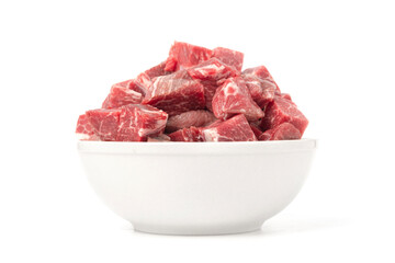 Raw beef cubes in a white ceramic bowl, fresh, natural dog or cat food, isolated on a white background.