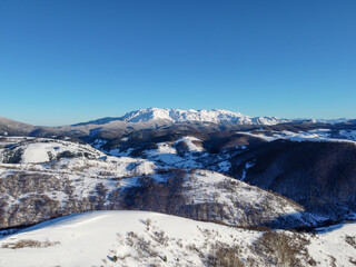 Fototapeta na wymiar Aerial drone view of hills and forest covered with a snow. Mountain in winter.