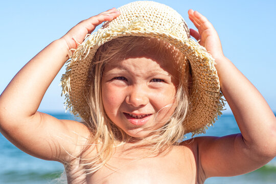 Cheerful child girl in Panama hat on the beach on a sunny day.