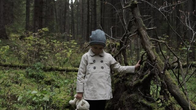 Little girl with teddy bear alone in a forest 