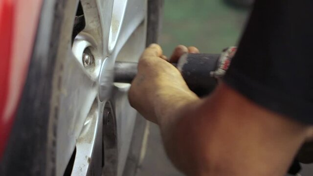 A repairman tightening nuts on car wheel