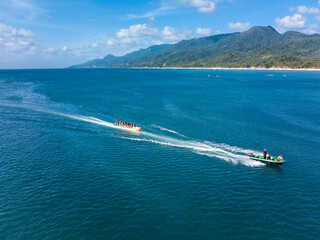 Aerial of a speedboat towing a banana boat near the beach. In Laiya, San Juan, Batangas,...